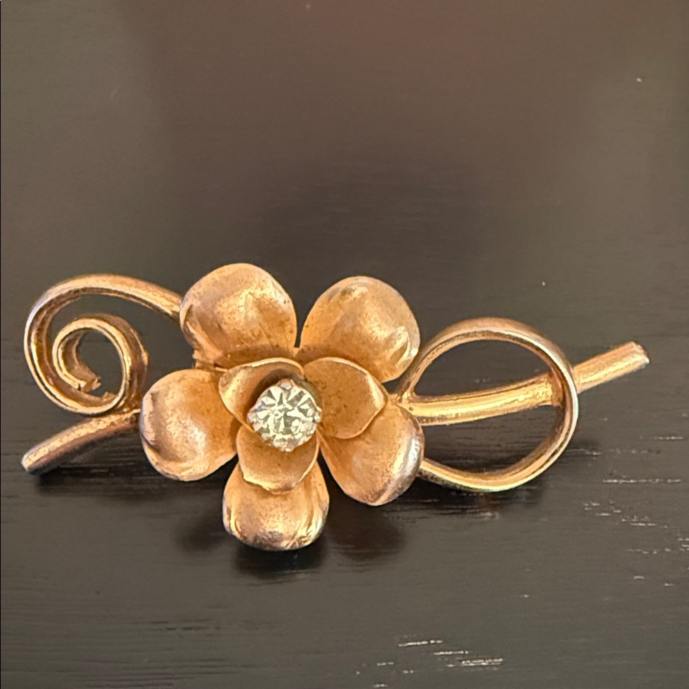 vintage gold-tone flower brooch with a rhinestone center signed Coro